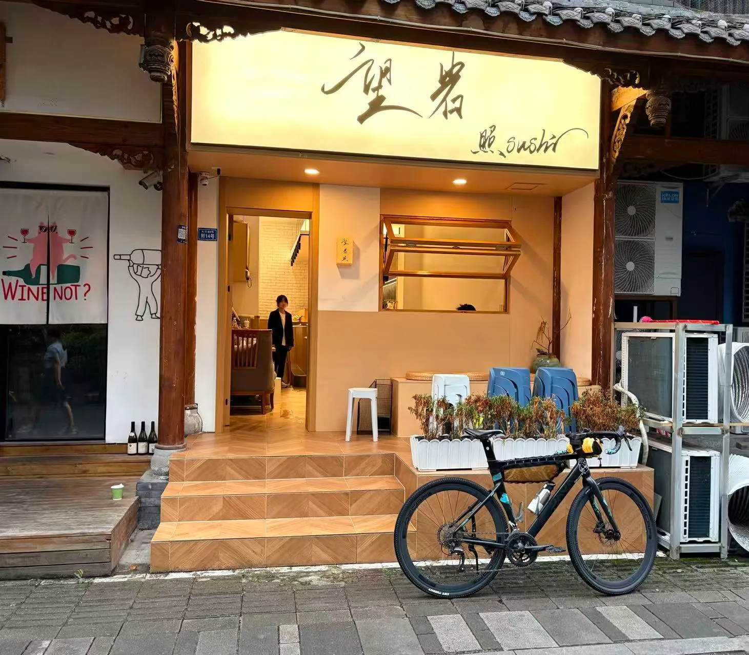 日料店门口，车停在门前，暖色灯光从店里透出来。