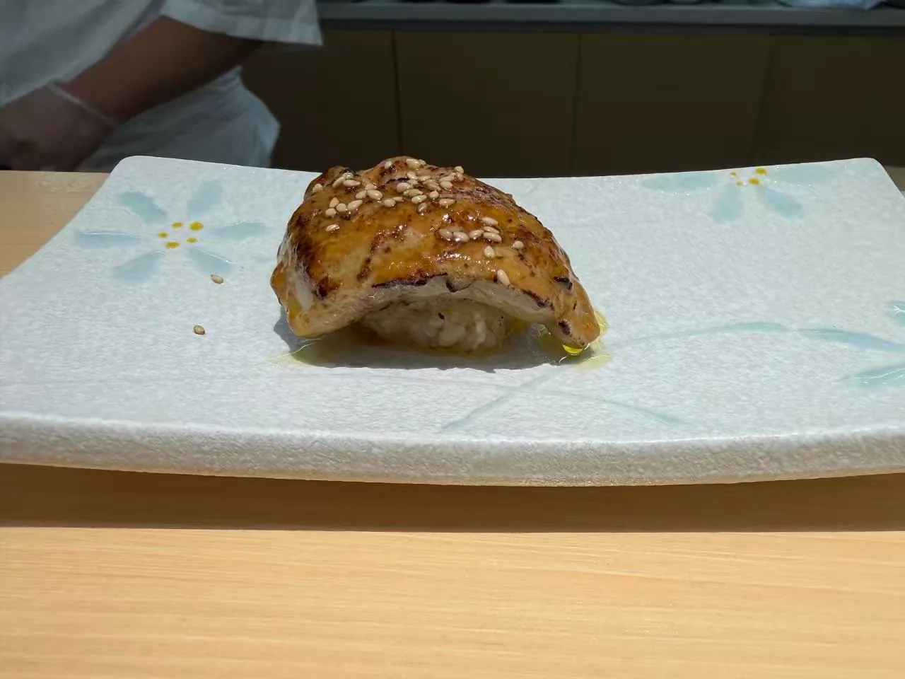 一枚香煎牛肉寿司放在浅色盘子上。